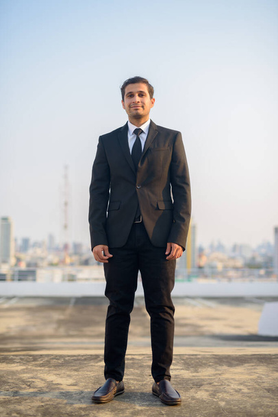 街を眺めながらスーツに身を包んだ若きペルシャ人ビジネスマンの全身撮影 - 写真・画像