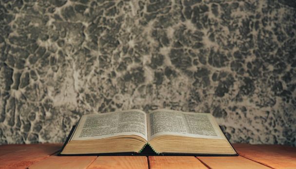 Open bible on a red old wooden table. Beautiful gray white wall background. - Photo, Image