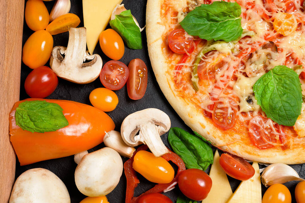 ingredients for vegetarian pizza on a dark background.tomatoes, mushrooms, peppers, Basil and pizza cheese . space for text. the view from the top. - Фото, изображение