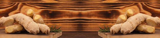 Radici di zenzero e ramoscelli di rosmarino su taglieri di legno. Immagine raddoppiata simmetricamente con spazio di copia. Ortaggi a radice fresca, concetto di cibo biologico sano
 - Foto, immagini