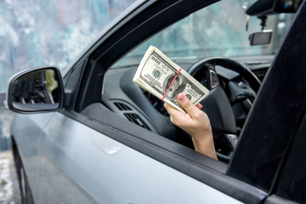 Weibliche Hände bieten Dolar-Bündel an. Fahrerin gab Bestechungsgeld - Foto, Bild