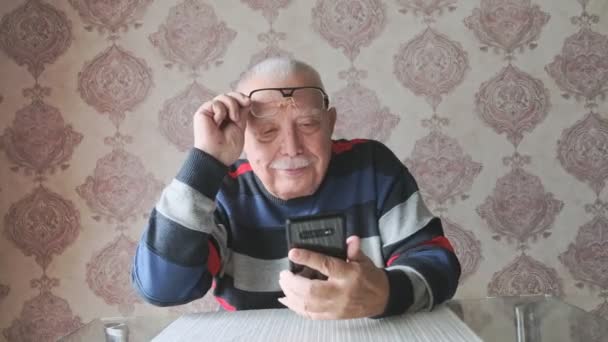 man with mustache wearing striped jumper looks at smartphone - Filmati, video