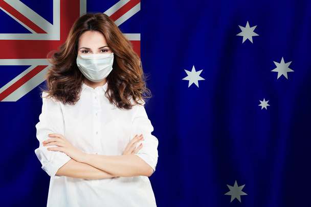 Glücklicher Wissenschaftler, Krankenschwester oder Arzt mit medizinischer Gesichtsmaske auf dem Hintergrund der australischen Flagge. Grippeepidemie und Virenschutz in Australien - Foto, Bild