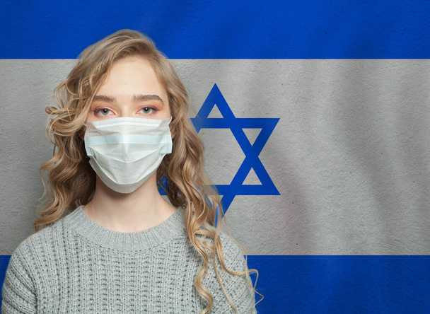 Νεαρή γυναίκα που φοράει μάσκα προσώπου με την εθνική σημαία Ισραήλ. Επιδημία γρίπης και έννοια της προστασίας από ιούς - Φωτογραφία, εικόνα