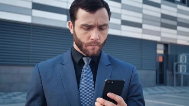 Portrait of Attractive Young Businessman using Smartphone standing near Modern Office Building. Wearing Classical Suit. Social Network. Apps. Smartphones. - Séquence, vidéo