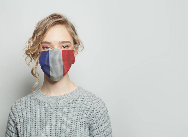 Młoda kobieta w masce z flagą. Koncepcja epidemii grypy i ochrony przed wirusami - Zdjęcie, obraz