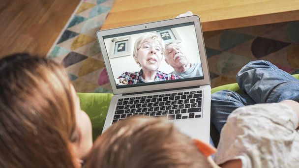 Joven mamá con hijo teniendo una videollamada en tiempo real con los abuelos. Familia de conexión con sus padres en la webcam. Tecnología moderna que conecta a personas de todas las edades concepto
. - Foto, imagen