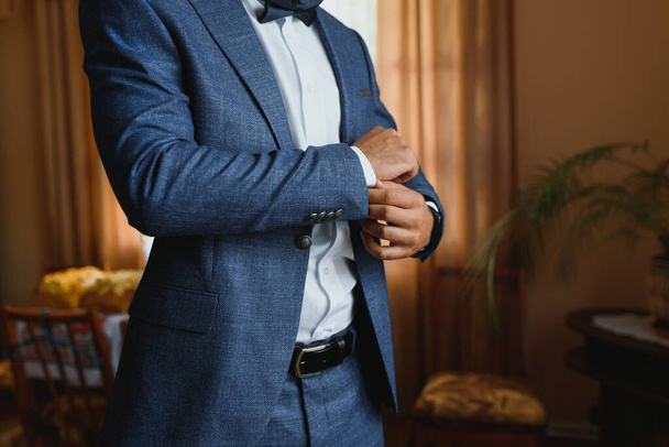 Close-up man puts on a gold watch with a leather belt, businessman is dressed in a stylish suit, a white shirt - Foto, imagen