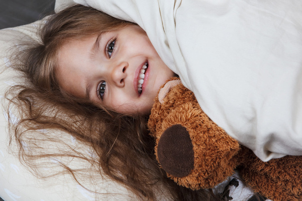 pretty little girl with toy in bed - Фото, зображення