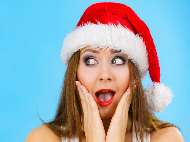Woman wearing santa claus hat surprised expression, on blue with copy space. Christmes time. - Photo, Image