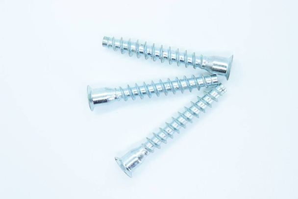 White metal screws located on a white background - Foto, Bild