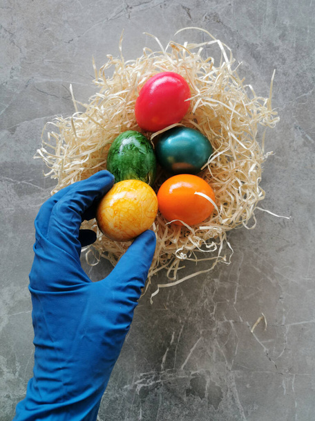 Female hand with protective glove holding easter egg, concept image coronavirus and easter holidays - Photo, Image