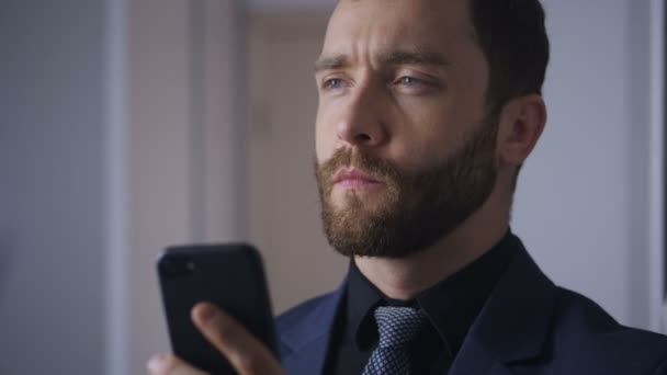 Portrait of confident businessman with a smartphone in his hands. The bearded boss solves the problem using a smartphone. - Video