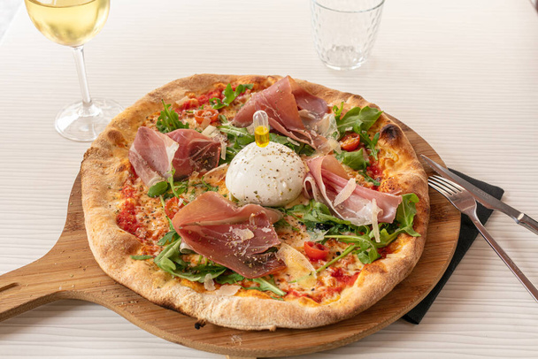 Pizza with mozzarella and raw ham served on a board - 写真・画像