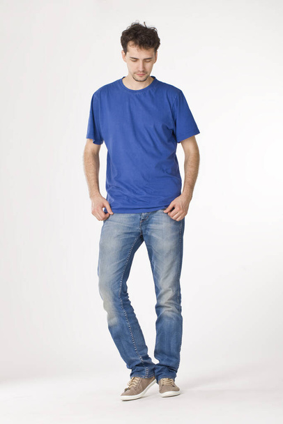 Young man in blue T-shirt standing and looking down - Foto, Bild
