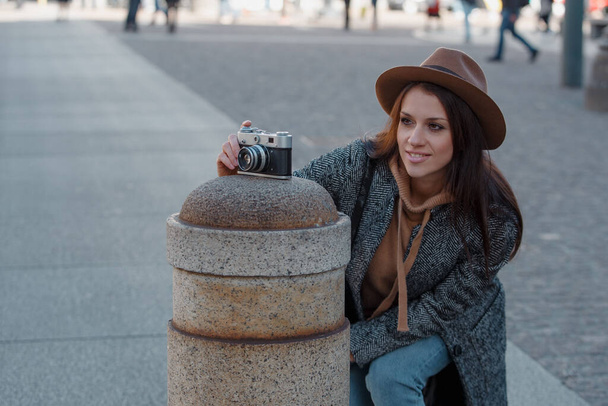 Beautiful young girl tourist put the camera on a column, photographs a column. - Fotó, kép