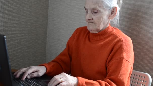 Elderly woman grandmother at a laptop - Кадри, відео