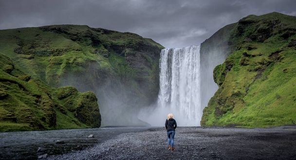 Young girl walking near Skogafoss waterfall in Summer, Iceland - Photo, image