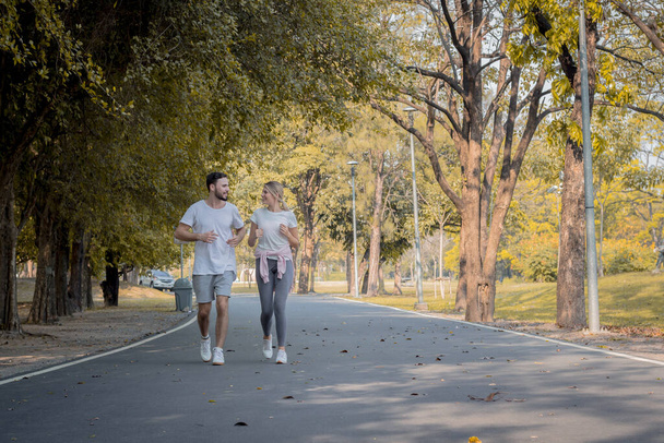 Mladé páry běhají v parku. Páry běhají po silnici v parku. Páry cvičí v parku. - Fotografie, Obrázek