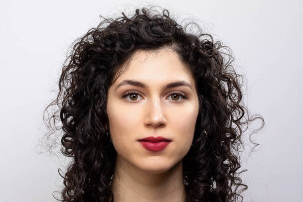 Attractive young brown haired woman looking at camera. Portrait of caucasian curly haired female. Isolated on white background. - Photo, image