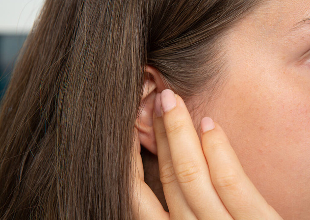 Girl touching her ear for hearing problems - Foto, afbeelding