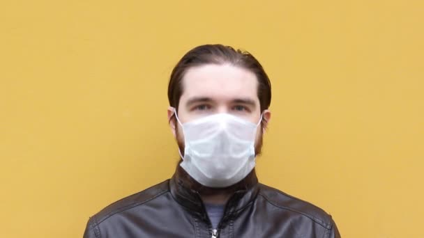 un homme adulte dans un masque jetable éternue. Instructions sur la façon de porter un respirateur et un masque correctement, protéger vos proches avec auto-isolement et précautions pendant le coronavirus
. - Séquence, vidéo