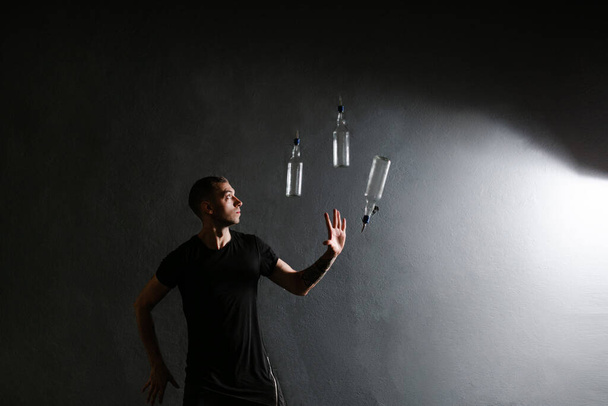 Hoogleraar barman jongleren drie glazen flessen op een evenement op grijze achtergrond - Foto, afbeelding