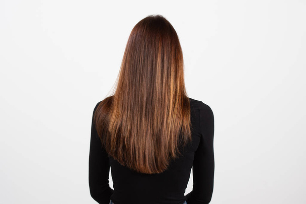 Brown-haired Women in black top rear view. Closeup of glossy straight long hair. Hair texture. Isolated on white background. Hair care concept - Photo, image