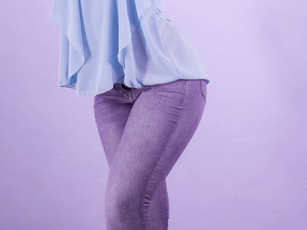 Kobieta w obcisłych dżinsach i niebieskiej koszuli, pokazująca swoje wspaniałe kształty ciała. Dobrze dopasowane spodnie - Zdjęcie, obraz