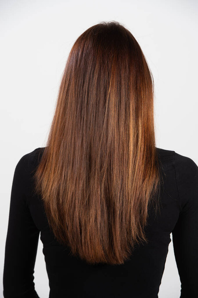 Rear view of freshly cut smooth long hair with highlights on a thin young model. Salon quality hair care products concept - Photo, image