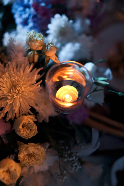 Святковий декор з квітами і свічкою на столі
. - Фото, зображення