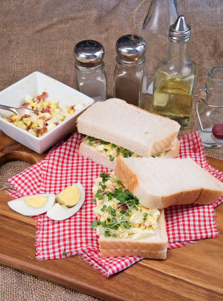 frisches Ei und Speck auf weißem Sandwich in rustikaler Küche - Foto, Bild