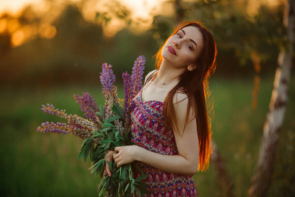 girl in a colored dress. Holds flowers in her hands. - Fotografie, Obrázek
