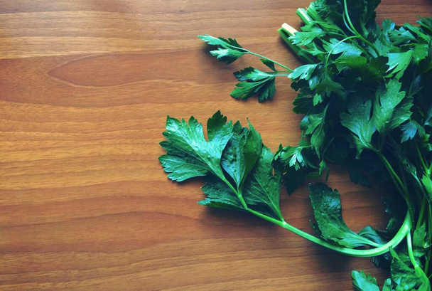 Fresh green parsley on a left side of a wooden table - Фото, изображение