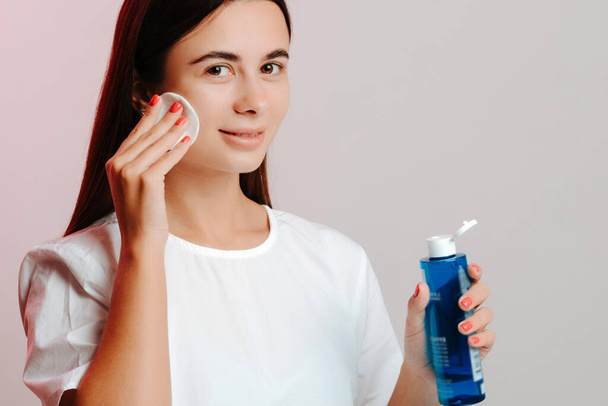 Makeup remove skin care. Closeup woman holding cotton swab and makeup remover liquid in hands. Woman cleaning her face with lotion and cotton pad. - Fotoğraf, Görsel