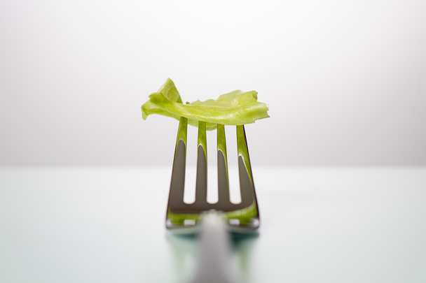 Foglia di lattuga sulla forchetta sdraiata sul tavolo
 - Foto, immagini