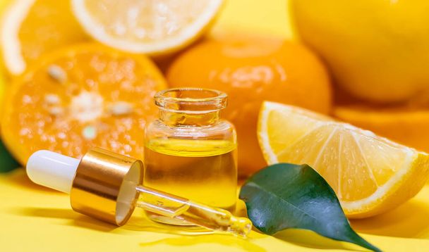 orange essential oil on a yellow background. Selective focus. - Foto, imagen