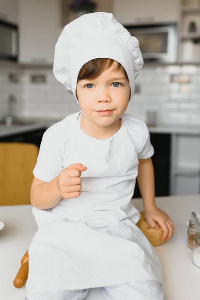 Little boy in kitchen.Cute boy wears a chef hat and apron. - Photo, Image