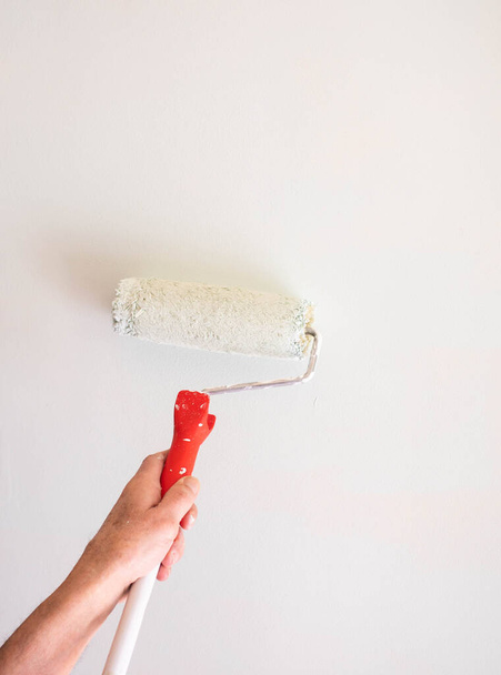 male hand painting wall with paint roller. Painting apartment, renovating with white color paint - Fotoğraf, Görsel
