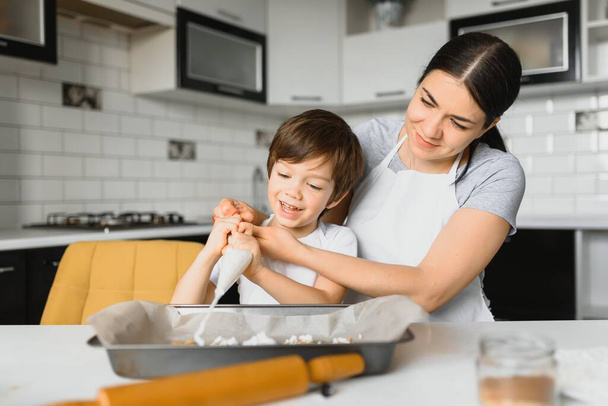 Ευτυχισμένη μητέρα και παιδί στην κουζίνα ετοιμάζοντας μπισκότα. - Φωτογραφία, εικόνα