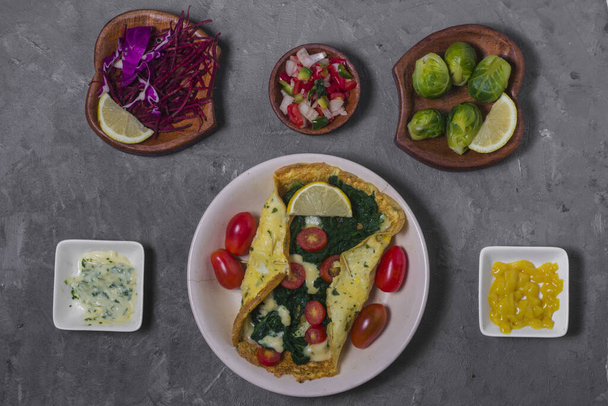 An omelet with spinach tomatoes and cheese with others vegetables and sauces - Photo, Image