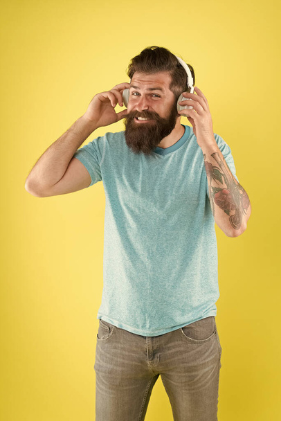 Freedom going wireless offers you is unparalleled. Hipster happy using modern wireless headphones. Wireless headphones designed to deliver clean sound. Bearded man listening music wireless gadget - Photo, image