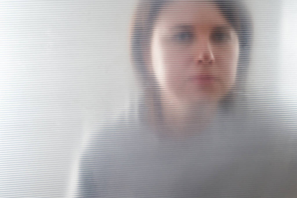 Silhouette de femme solitaire floue regardant à travers le plastique transparent
 - Photo, image