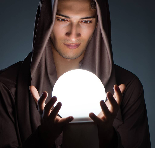 Jovem feiticeiro com bola de cristal no quarto escuro - Foto, Imagem