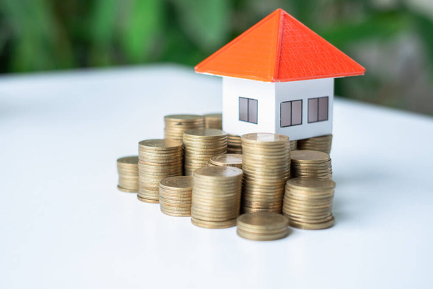 Üstünde turuncu bir çatı olan bozuk para yığını. Emlak yatırım planlaması ve fikirler için ev veya kredi satın almak için para tasarrufu kavramları riskli olabilir. Metin koymak için boşluk var. - Fotoğraf, Görsel