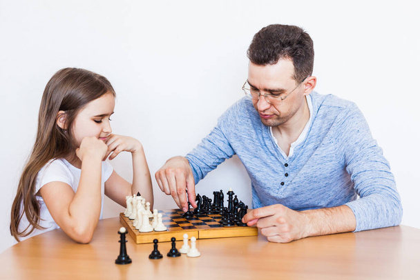Girl and dad play a game at home, chess, puzzle for brain development, mental intelligence, child development, school, home, quarantine, vacation, time with family - Photo, Image