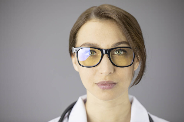 Sexy doctora en gafas con lentes amarillas está mirando a la cámara
 - Foto, Imagen