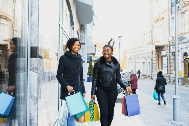 young black women going shopping. African American girls with shopping bags go shopping - Foto, Imagen