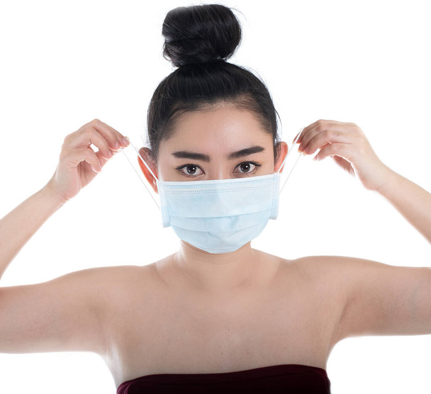 Bella giovane donna asiatica che indossa una maschera medica per proteggere dalle malattie respiratorie aviotrasportate come l'influenza covid-19 PM2.5 polvere e smog, concetto di infezione da virus della sicurezza delle donne, guarda fotocamera
 - Foto, immagini
