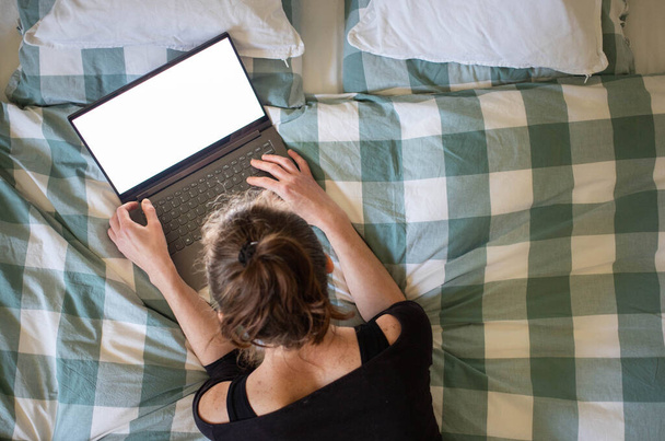 mujer usando el ordenador portátil o tableta en la cama pantalla vacía blanca para el espacio de copia
 - Foto, imagen